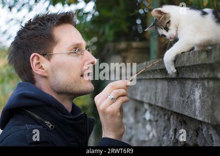 A man playing with a young domestic cat Stock Photo