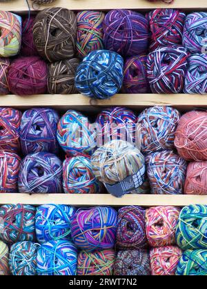 Many colourful balls of wool on a wooden shelf Stock Photo