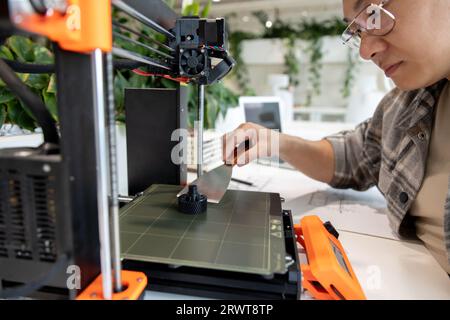 Asian designer engineer using 3D printer in laboratory and studying ...