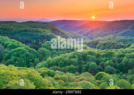 The fresh green of Jogakura Valley, Mt. Iwaki and the setting sun as seen from Jogakura Ohashi Bridge Stock Photo