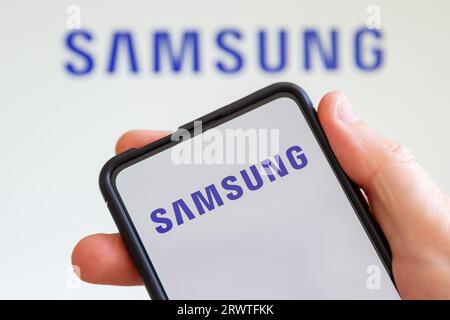 Stuttgart, Germany - July 20, 2023: Hand holding a mobile phone with Samsung logo of the television and smartphone manufacturer computer screen in Stu Stock Photo