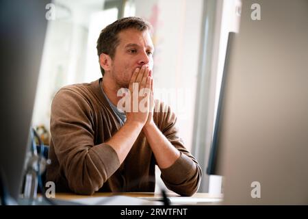 Overworked tired employee, programmer at workplace in office being unhappy Stock Photo