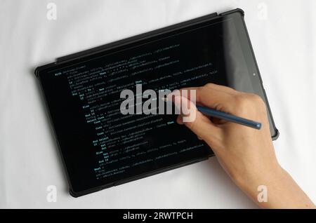 Programming and coding concept. A hand with a pencil writes a program listing on the screen Stock Photo