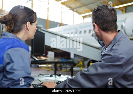two mechanics working on aircraft in a hangar Stock Photo