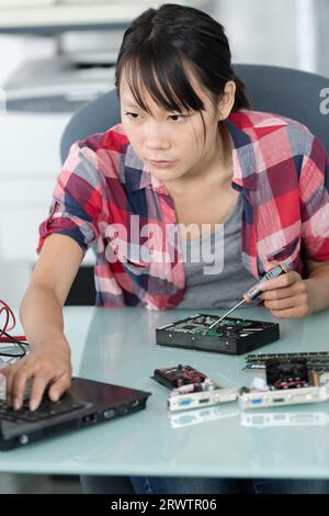 female asian computer technician using laptop Stock Photo