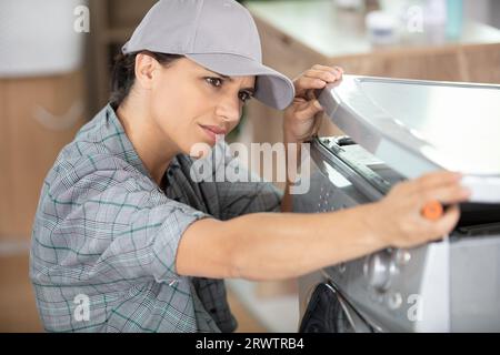 female plumber repairing washing machine Stock Photo