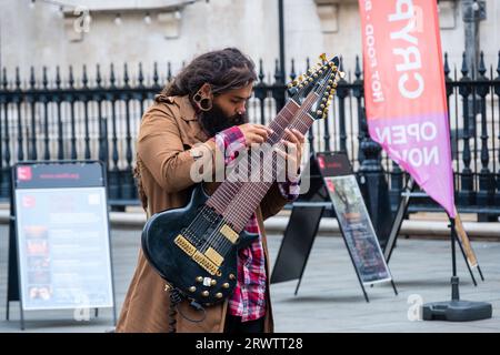 LONDON- SEPTEMBER, 18, 2023: Busker playing a 12 string guitar in London’s West End Stock Photo