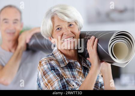 senior couple carrying a carpet moving in to new home Stock Photo