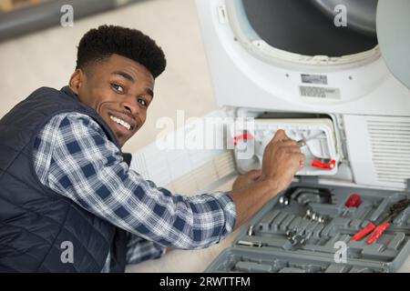 plumber installing washing machine in domestic bathroom Stock Photo