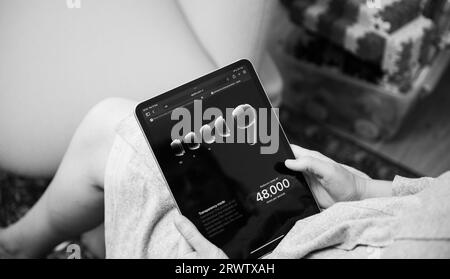 London, UK - Sep 13, 2023: a woman is engrossed in her iPad Pro, reading about Apple Computers' Transparency Mode and Noise Reduction features for the AirPods Pro 2nd Generation. Stock Photo