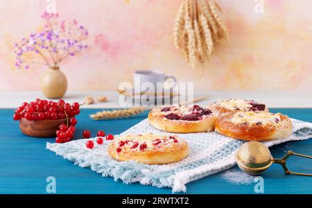 Baked fruit pies with fresh summer beries, currants, cherries, blackberries, blueberries and crumble on blue wooden table, low angle of view, selectiv Stock Photo