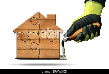 Manual worker with work gloves holding a dirty trowel and a small wooden house formed from jigsaw puzzle pieces. Isolated on white background. Stock Photo