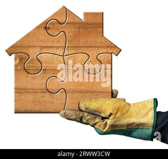 Hand with work glove holding a small wooden house formed from jigsaw puzzle pieces. Isolated on white background. Construction industry concept. Stock Photo