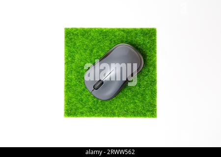Top view of a computer mouse placed on a tiny square patch of green synthetic grass isolated on whit background. Stock Photo