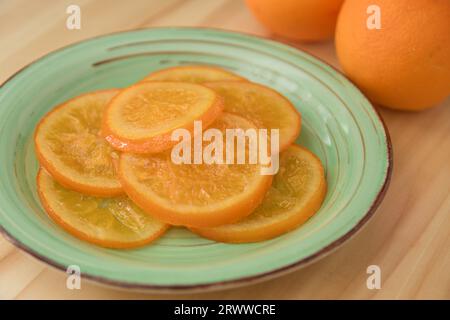 Close-up of a plate with slices of candied oranges next to two whole oranges for the decoration of the roscón de reyes Stock Photo
