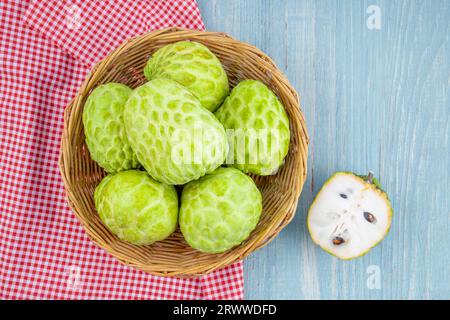 Sugar apples or custard apples in a wooden weave basket on wooden table. Stock Photo