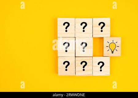 Wooden cube with hand drawn light bulb next to the cubes with question marks. Concept of problem solving, creativity, idea or innovation. Stock Photo