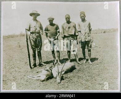 Mr Bungey stands with his bicycle in front of a fence, behind which are a couple of dozen ostriches in a paddock, apparently on Paul Rainey's farm. The explorer and film-maker Paul Rainey had purchased land in Naivasha a couple of years previously, and shot some of his early films there.  Original manuscript caption: 'Ostrich', Paul Raineys farm. Naivasha 1913. Stock Photo