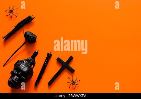 Black docoration accessories put on orange background. Halloween party concept. Stock Photo