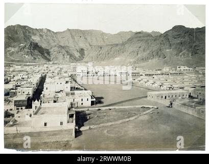 View of Aden, taken from a high vantage point with rocky mountains in the background. The buildings within the city are laid out in a grid-like formation. Caption reads: Aden. Stock Photo