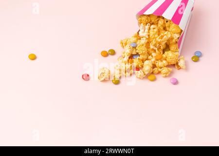 Caramel popcorn and dragee candies on pink background. Copy space Stock Photo
