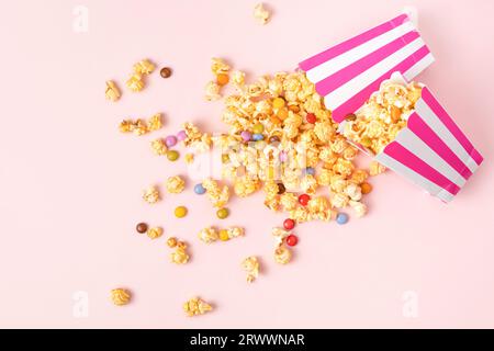 Caramel popcorn and dragee candies on pink background. Flat lay, top view. Stock Photo