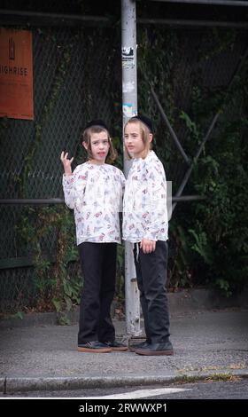 Orthodox Jewish brothers dressed alike have a chat while they wait for their school bus to ytake them to yeshiva. On Lee Avenue in Williamsburg, Bklyn. Stock Photo