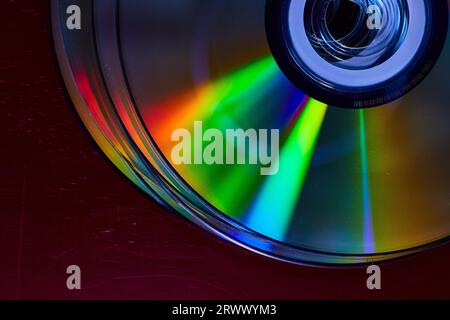 Abstract stack of four bright silvery CDs with reflective rainbow colored bursts of light on surface Stock Photo