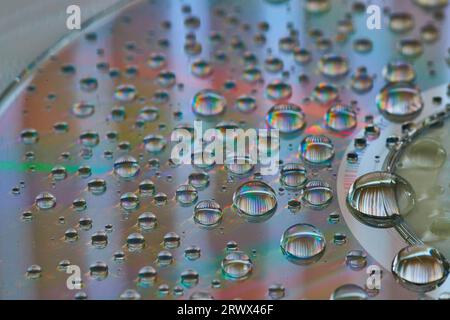 Side view of rainbow water drops in macro view of metallic surface abstract background asset Stock Photo