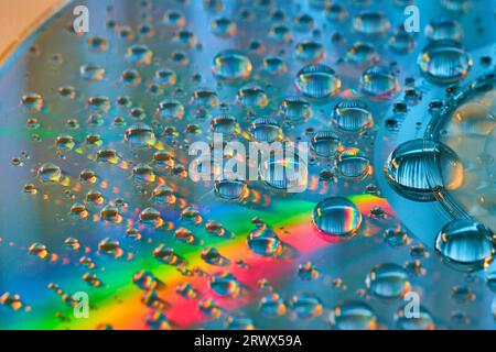Macro side view of rainbow water drops on metallic surface abstract background asset Stock Photo