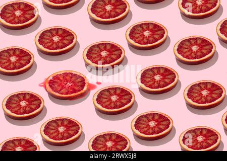trendy seamless flat lay pattern of juicy red orange or grapefruit slices on pastel pink background funny summer concept Stock Photo