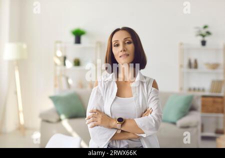 Portrait of confident middle aged woman standing arms crossed and looking at camera Stock Photo