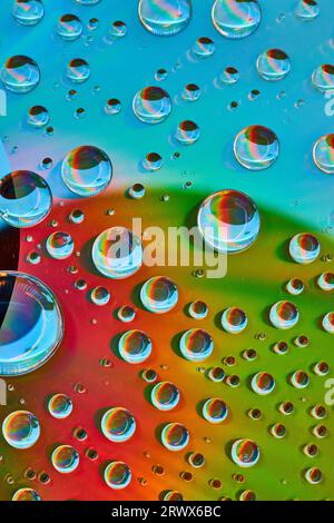Abstract background asset of large to small water droplets on green and red surface with blue arc Stock Photo