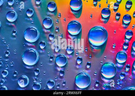 Silvery blue water droplets on colorful red and orange metallic surface background asset Stock Photo