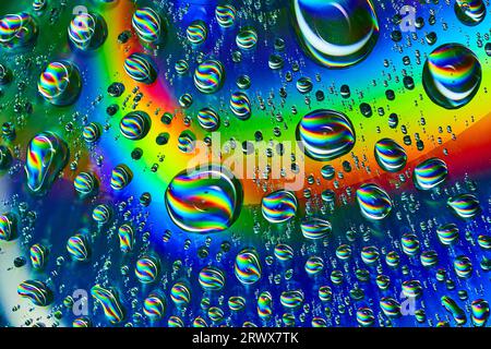 Swirls of rainbow colors inside wobbly bubbles on dark silvery blue rainbow burst background asset Stock Photo