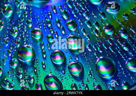 Silvery raindrops with blue and purple and green swirls on reflective metallic background asset Stock Photo