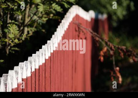 Helsinki / Finland - SEPTEMBER 18, 2023: Selective focus closeup of a wooden picket fence. Traditional Nordic red soil fencing. Stock Photo