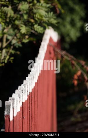Helsinki / Finland - SEPTEMBER 18, 2023: Selective focus closeup of a wooden picket fence. Traditional Nordic red soil fencing. Stock Photo