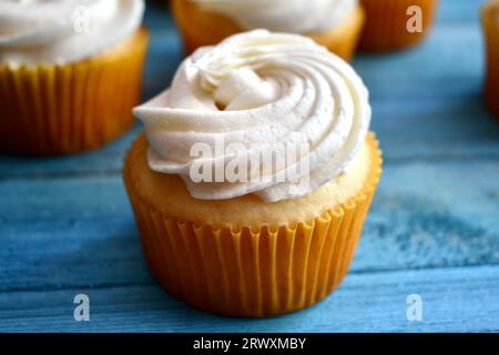 Vanilla cupcake in a yellow paper cup on a blue wood background Stock Photo
