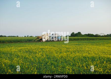 A tractor with a trailed sprayer in the field. A farmer works on a tractor in the field. Stock Photo