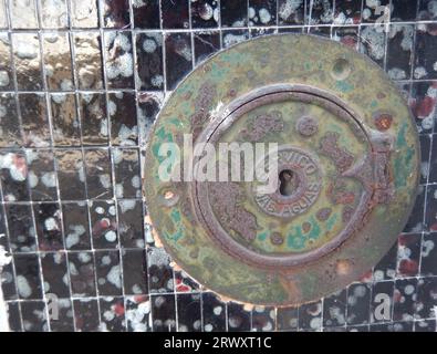 Old round door of a water meter located on the facade of a house Stock Photo