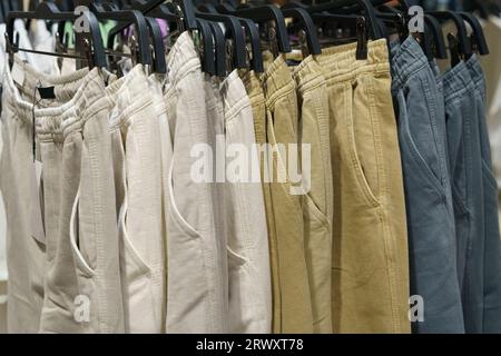 mens trousers hang on hangers in a clothing store close up background