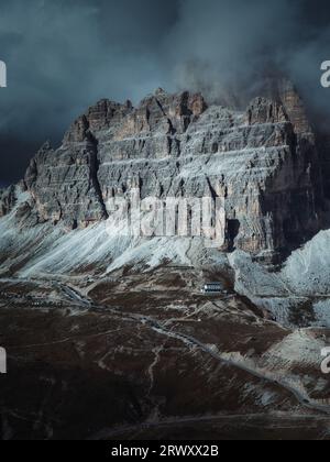 Dramatic Dolomites mountain cliffs in Italy, with dark storm clouds, mist and rugged limestone peaks creating a moody alpine landscape Stock Photo