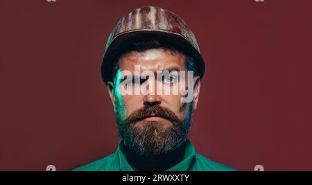 Closeup portrait of mechanical worker in safety helmet. Handsome bearded man in hardhat. Serious architect, engineer or designer in protective wear Stock Photo