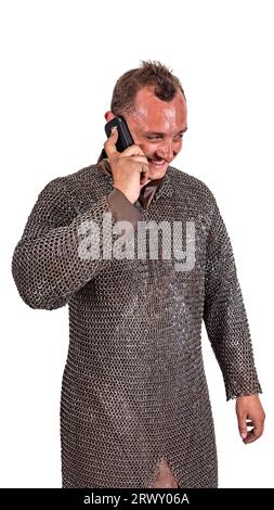 Medieval knight in armor talking on a cell phone. Isolated on white. Stock Photo
