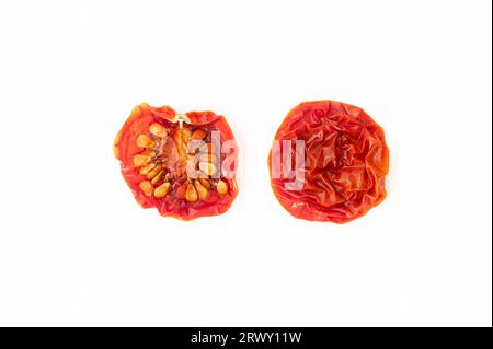 A dried cherry tomato sliced in half on white background Stock Photo