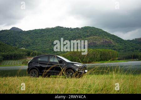 Black car parked near a lake with a hill background on a rainy season Stock Photo