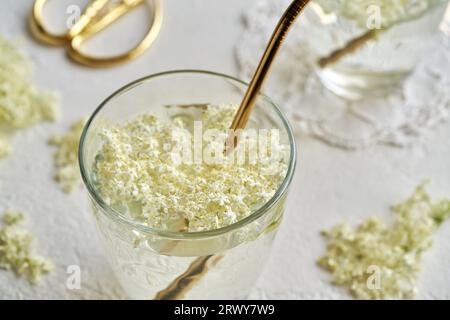 Closeup of elderberry flowers in a glass of lemonade with a golden ecological metal straw Stock Photo