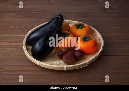 eggplant persimmon chestnuts assorted platter isolated on wooden table Stock Photo