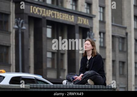 Girl sitting with closed eyes on the bench against the State Duma in Moscow Stock Photo